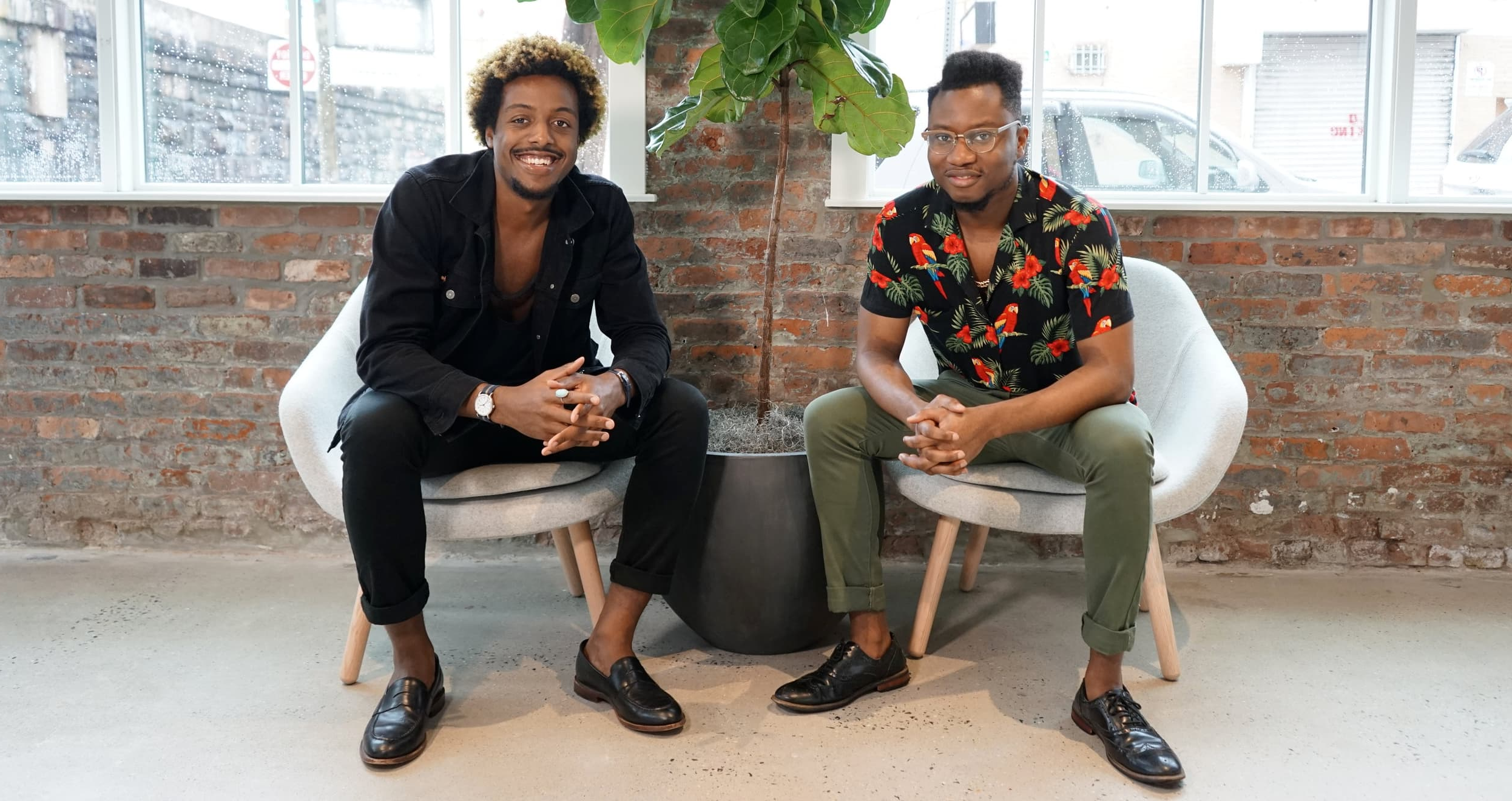 Ivan Alo and LaDante McMillon sitting in their office in front of a large plant